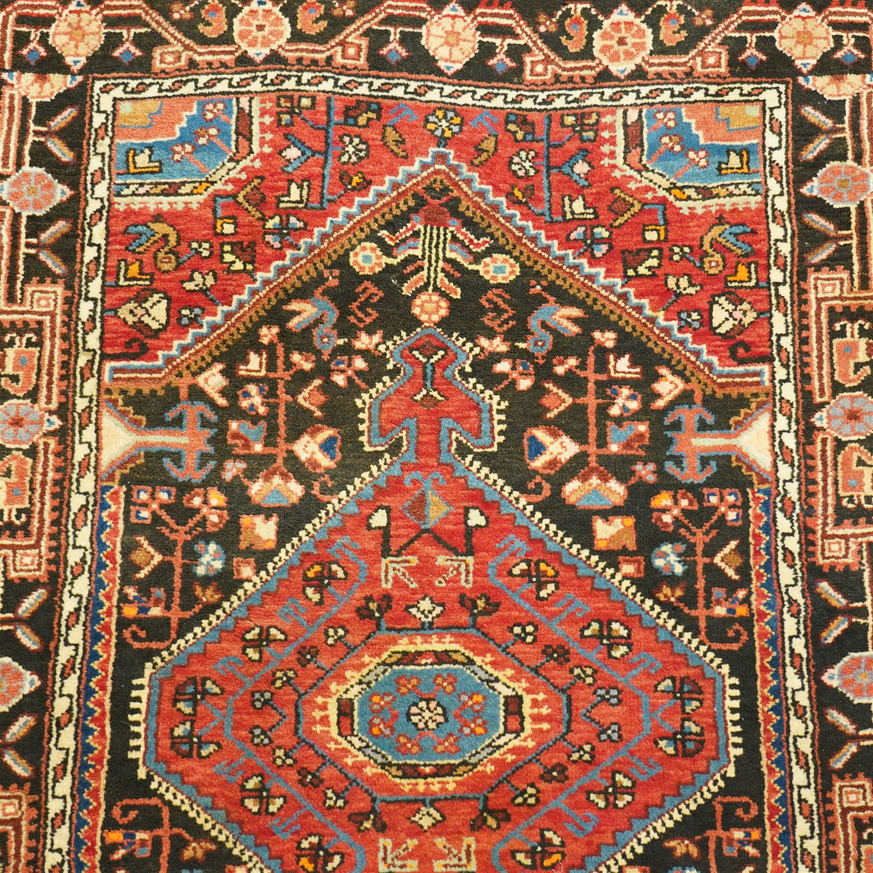 North West Persian Heriz hand-knotted rug, indigo and madder red field with a central angular medallion with stylized floral and geometric motifs within multiple patterned borders with fringe ends 