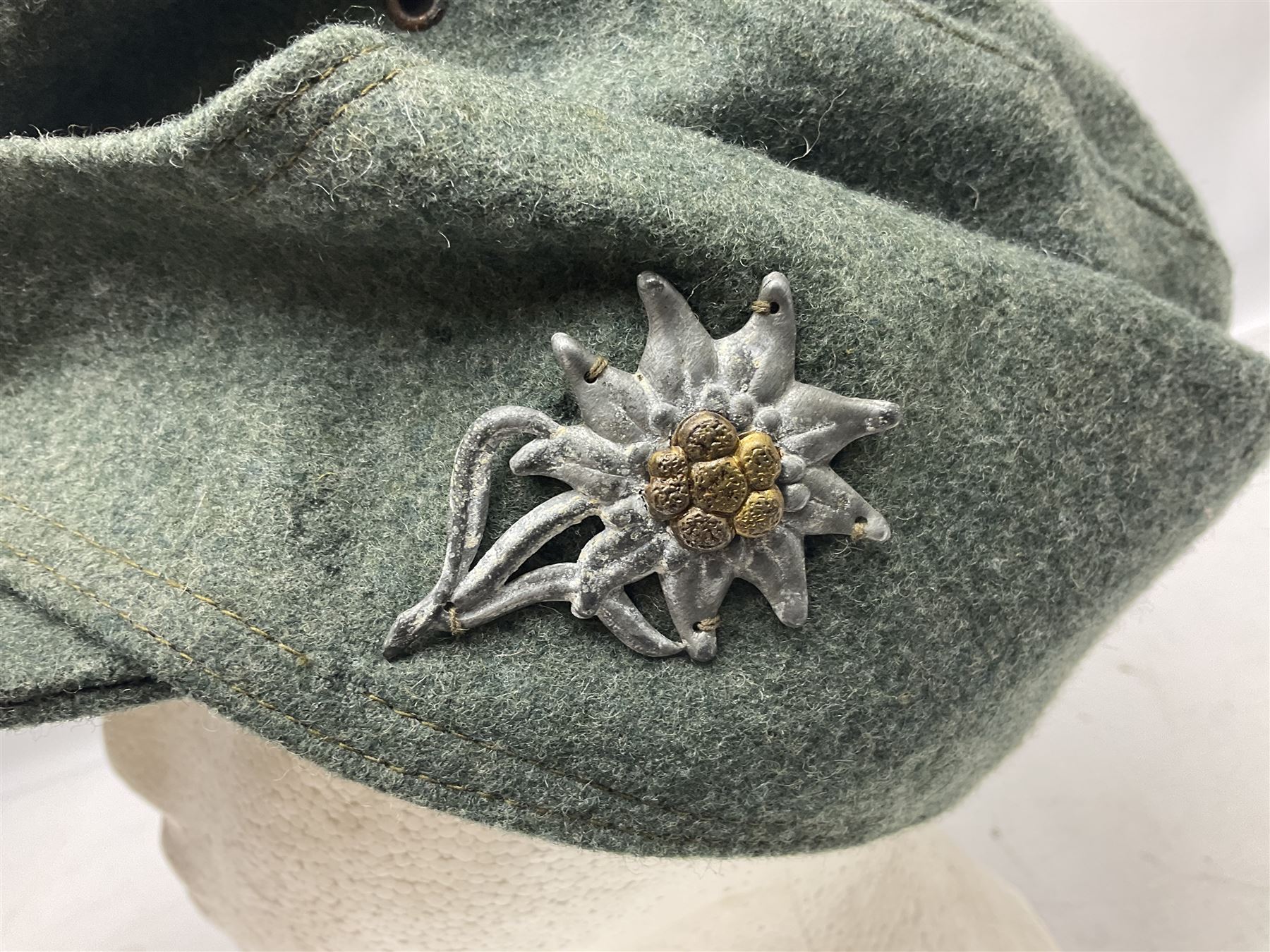 WW2 German Army M43 field cap with triangular cloth eagle and roundel badge and metal edelweiss badge for mountain troops; faintly stamped '5 VMF(?)'