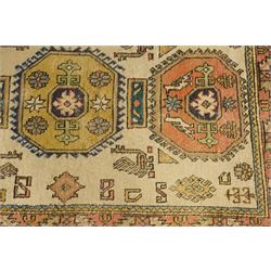 Two Caucasian designed rugs comprising a flatweave and hand-knotted rug, Caucasian design flatweave, cream ground with three large blue geometric medallions surrounded by stylised birds and geometric motifs, enclosed by repeating geometric border, fringed ends, H176cm, W102cm; hand-knotted Caucasian rug, ivory ground with three polychrome octagonal medallions surrounded by stylised animals, flowerheads and geometric motifs, enclosed by salmon pink geometric border, fringed ends, H163cm, W106cm