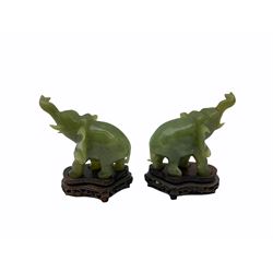 Pair jade figures modelled as elephants with trunks raised, with accompanying carved and pierced wooden stands, figures H9cm 
Provenance: purchased Hong Kong in the 1980s