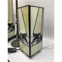 Two Tiffany style table lamps, including an example with cast brushed metal base and bell shaped shade, H67cm and a rectangular example, with floral decoration upon a cream ground, H46.5cm, together with a smaller glass table lamp with similar Tiffany style shade