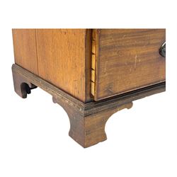 Early 19th century mahogany linen press cupboard, projecting moulded cornice over figured frieze, two panelled doors enclosing shelves, fitted with two short and two long cock-beaded drawers, on bracket feet 