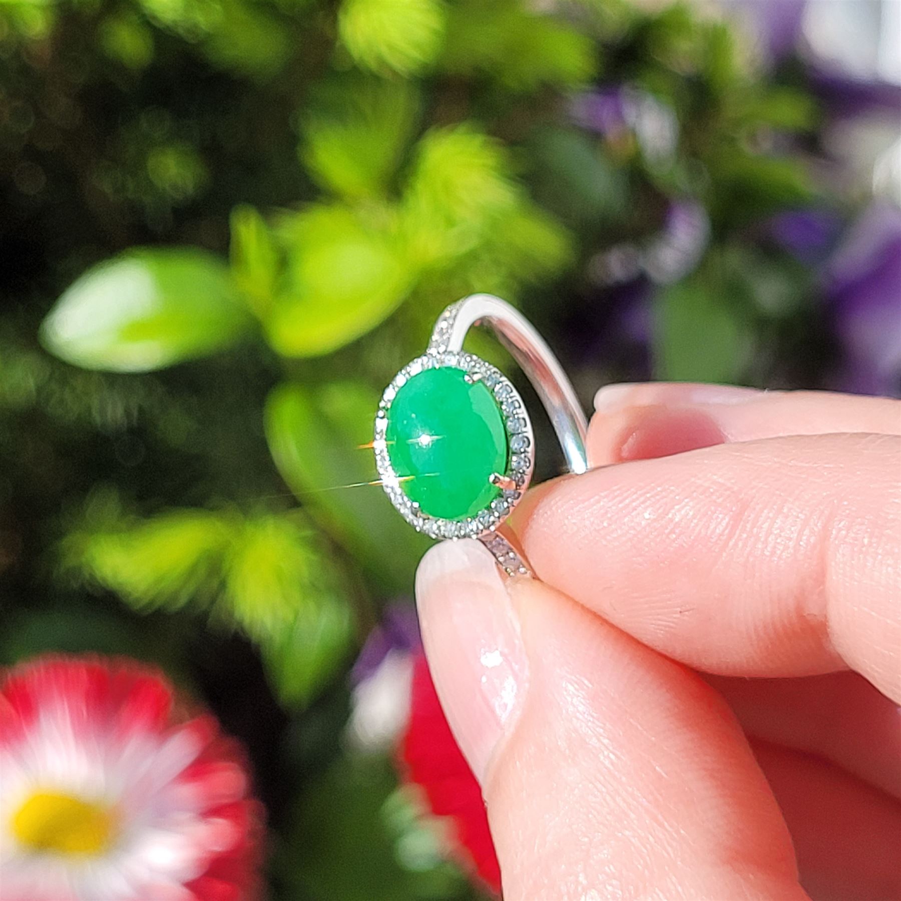 Platinum jadeite and diamond cluster ring, single oval cabochon cut jadeite of 2.20 carat, surrounded by round brilliant cut diamonds and diamond set shoulders, stamped Plat