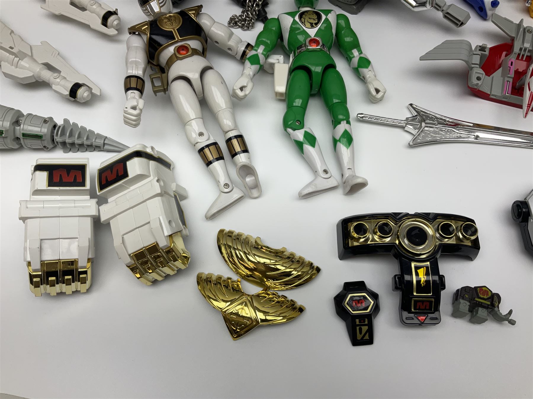 Collection of early 90s Mighty Morphin’ Power Rangers Zords, figures and accessories. Titanus the Carrier Zord, marked Bandai 1991; Green Dragonzord, incomplete; 1994 White Tigerzord with original instruction manual; 1993 Triceratops Dinozord, Mastodon Dinozord and Sabertooth Tiger Dinozord, Pterodactyl Dinozord, missing guns; with 1993 Power Morpher and original Power Coins, with further related figures, accessories and weapons