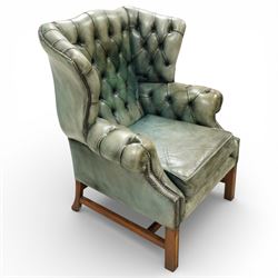 Georgian design mahogany framed wingback armchair, upholstered in rustic pale green buttoned leather with loose seat cushion, raised on square supports united by H-stretcher