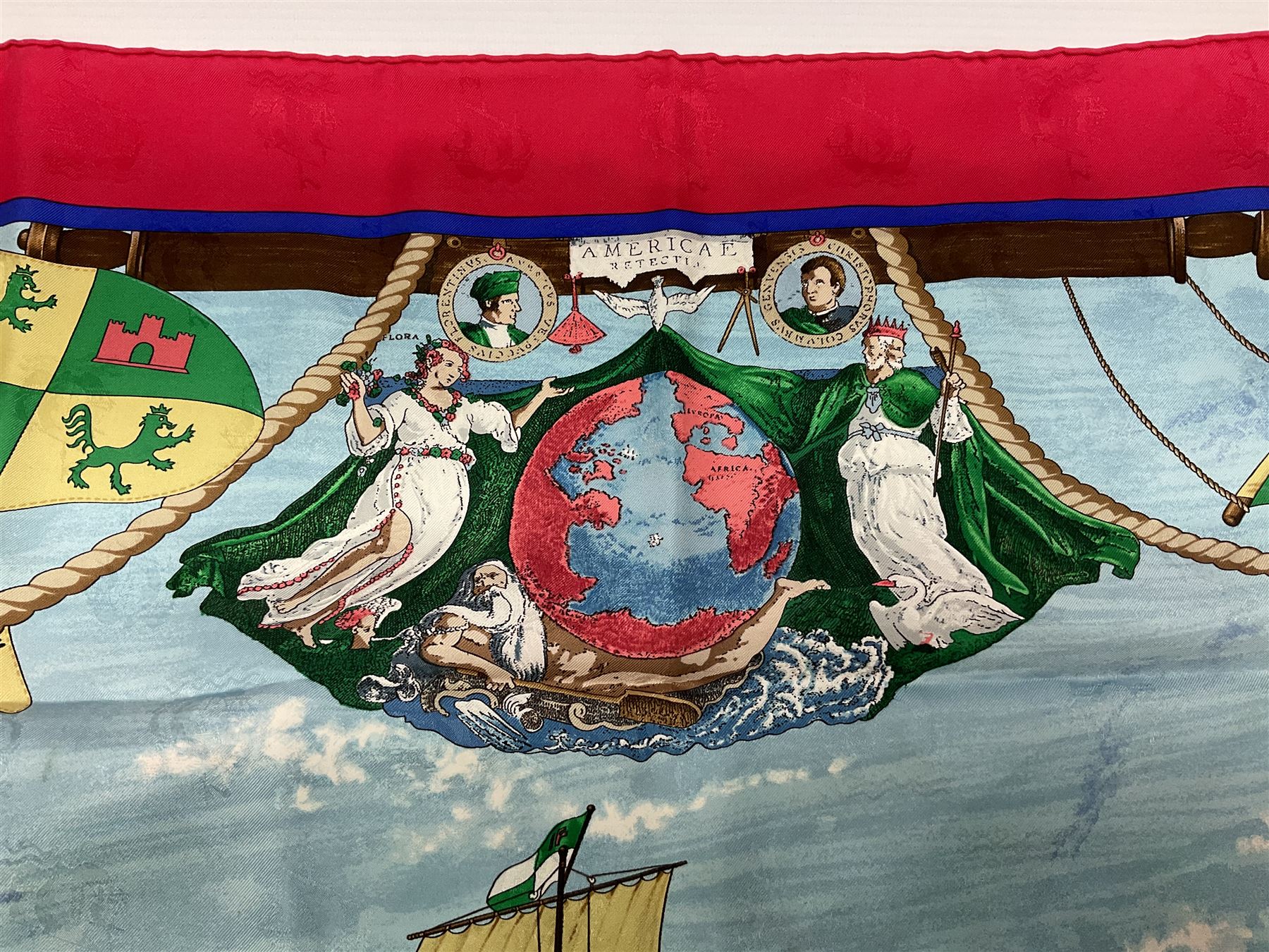 Hermès 'Christophe Colomb Découvre l'Amérique' jacquard silk scarf, designed by Carl de Parcevaux in 1992, limited edition for the bi-centenary of the discovery of America, printed with a central image of Christopher Columbus' ship at sea, surrounded with colourful stylised feathers, birds, flags, globes, shells and flowers, contained within vibrant red border, with rolled hand stitched edges and Hermes material label, 87cm square