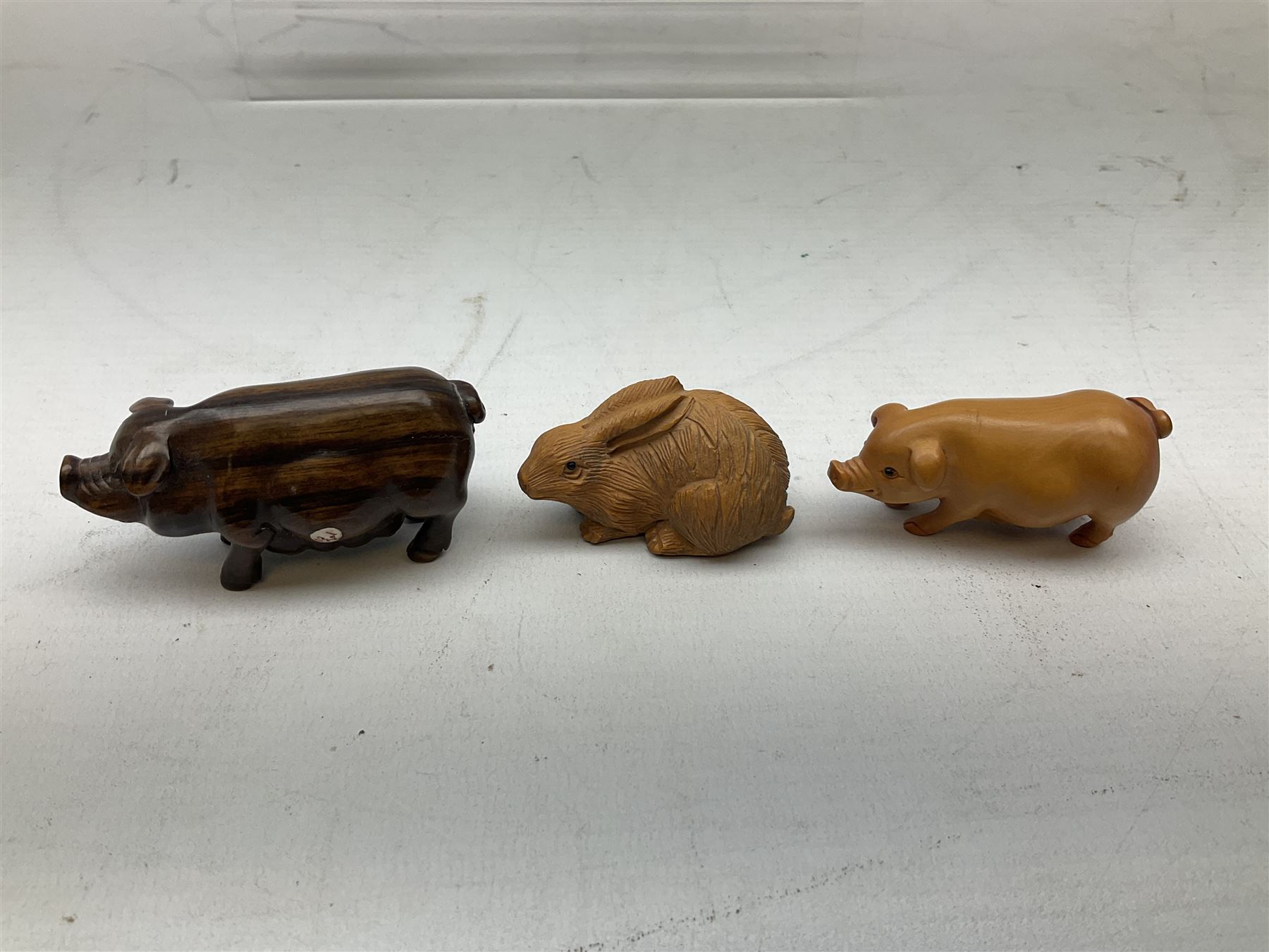 Group of ten Japanese netsukes, comprising eight carved wooden examples, and two ivorine examples, of various form, examples modelled as pigs, owl, mouse with tortoise upon its back, birds, rabbit, etc. 