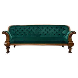 Victorian mahogany settee, upholstered in green buttoned fabric, moulded frame and scroll carved arm terminals, turned supports on castors