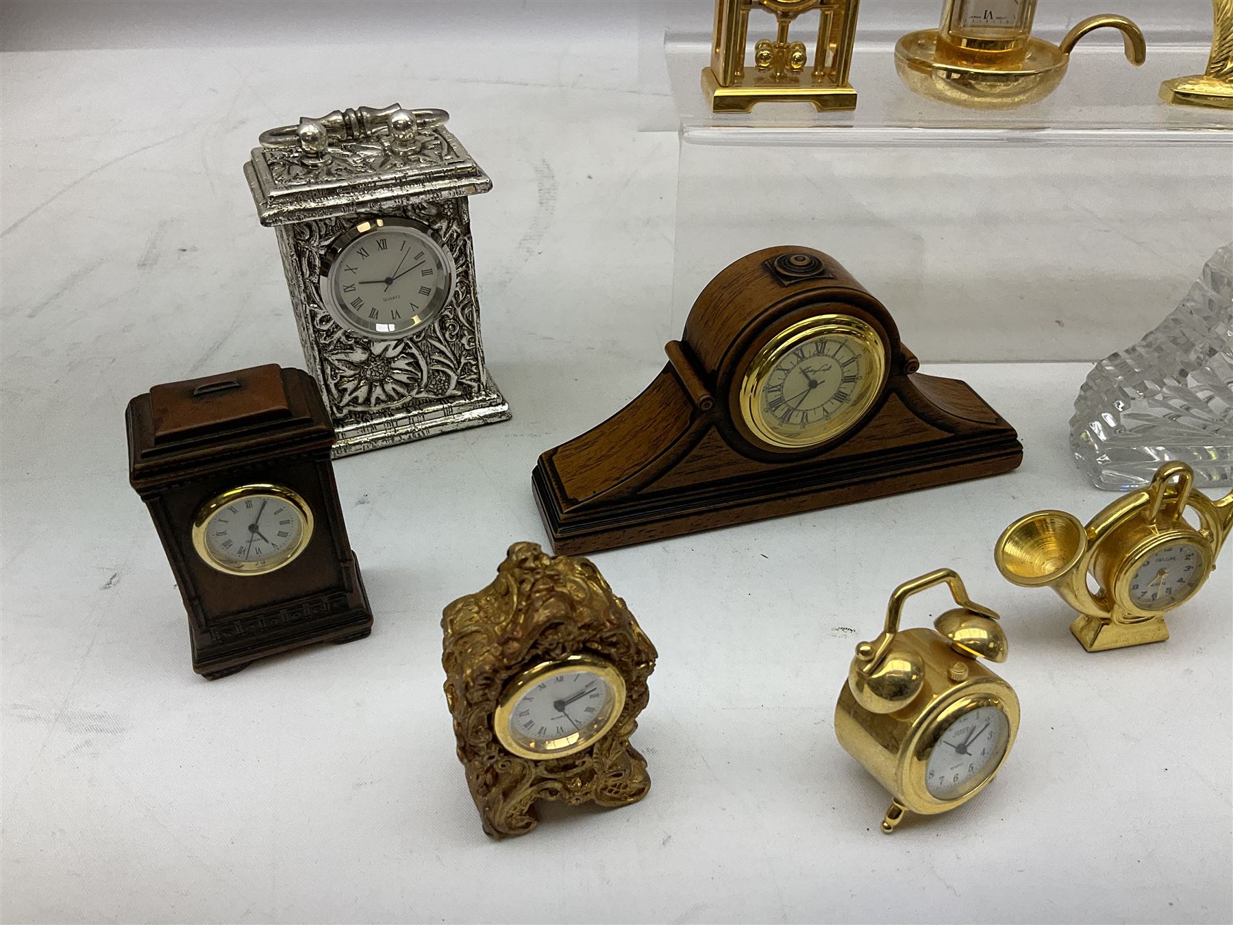 Collection of miniature clocks, predominantly with quartz movements, to include example modelled as an armchair, Edinburgh crystal glass example, clock modelled as a flower, sewing machine etc