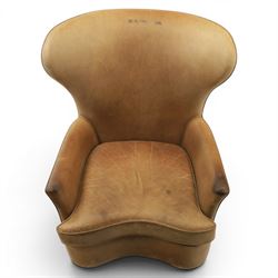 20th century tan leather armchair, the curved wing back above low square arms, shaped loose seat cushion with piped edge, close-nailed side detail, raised on concealed castors