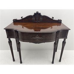 Early 20th century Hepplewhite style serving table, raised fleur-de-lis feather back with fluted detail and flower head mounts, the shaped top with carved foliate edge over single central drawer with applied urn motif, turned and reeded acanthus supports with recessed castors