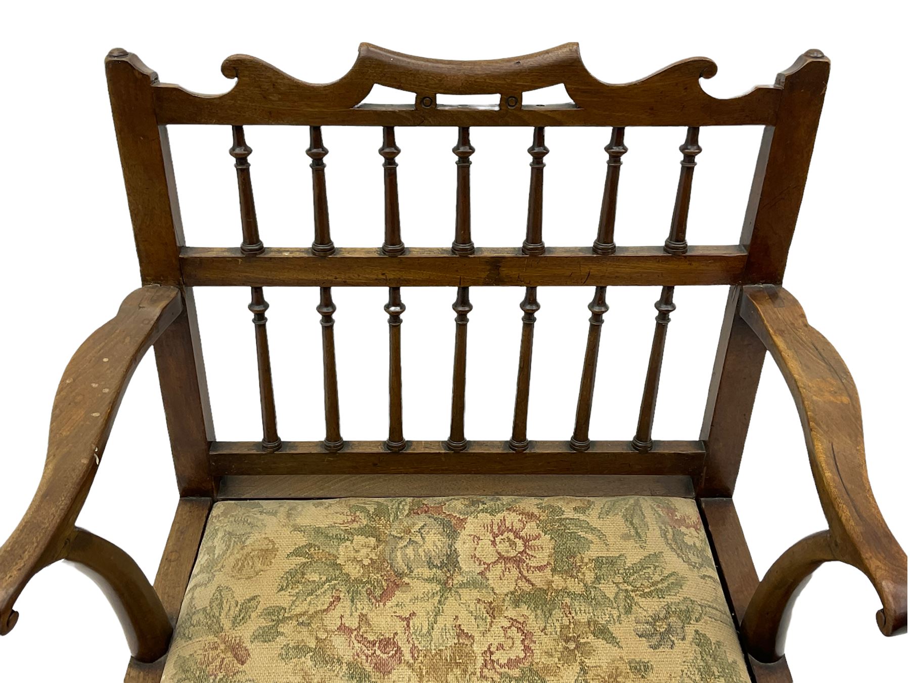 Late 18th century walnut 'Drunkard's' chair, the shaped cresting rail over spindle back, wide set seat with upholstered drop in cushion, shaped arms with scroll carved terminals, sledge supports with bracket feet joined by plain stretchers 
