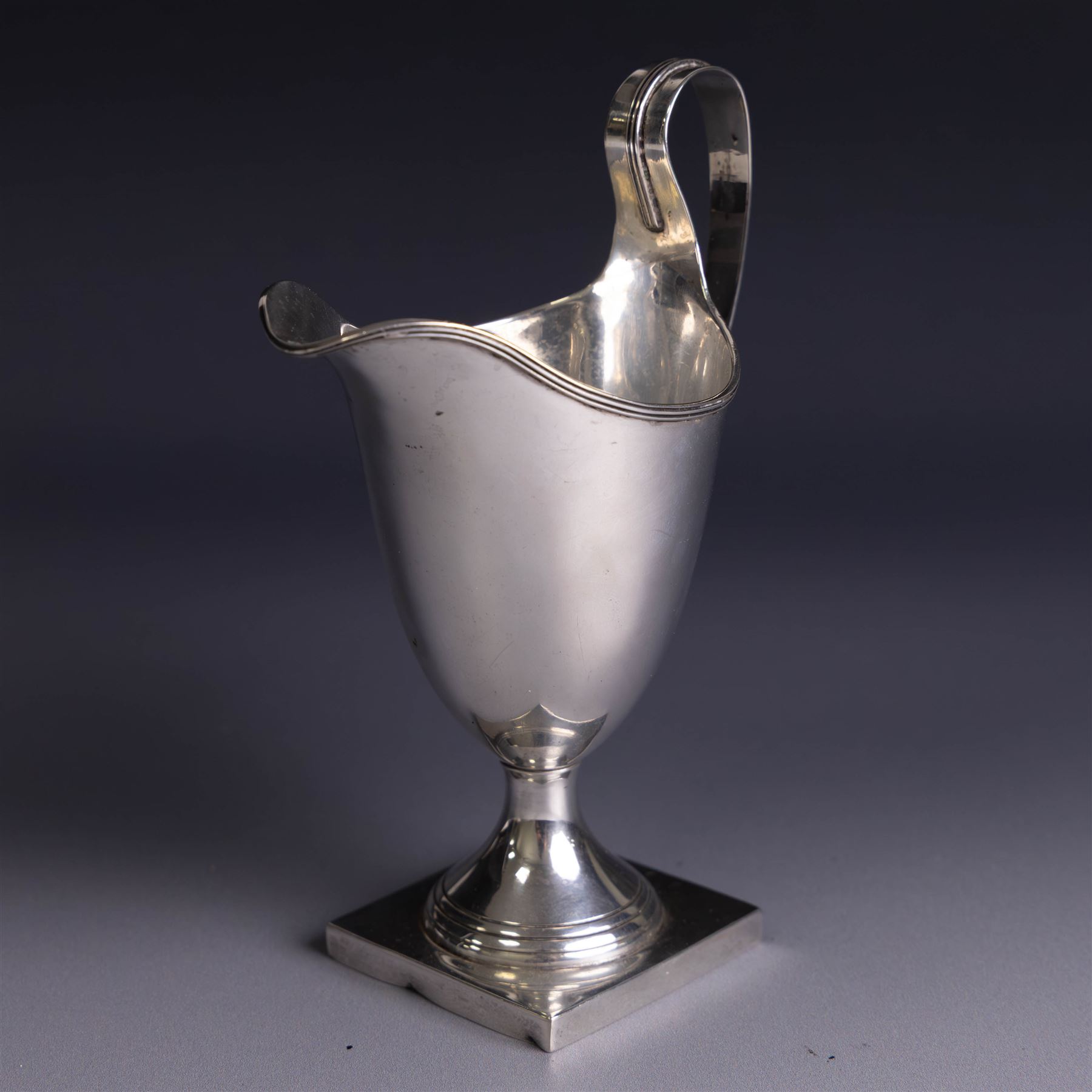 Edwardian silver helmet shaped cream jug, upon a square base, hallmarked John Rose, Birmingham 1905, together with a 1930s silver christening mug with engraved initials to body, hallmarked Aaron Lufkin Dennison, Birmingham 1936, jug including handle H13cm
