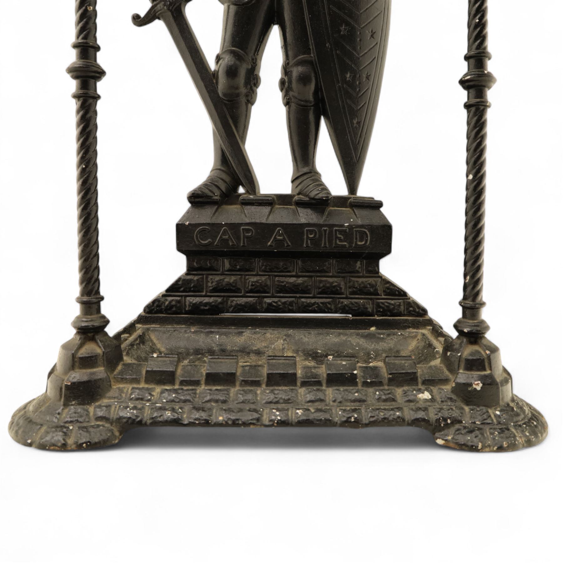 Early 20th century painted cast iron hall stand, formed as a standing armoured figure with red and yellow feathered crest, twin rails and integral drip tray with castellated edge