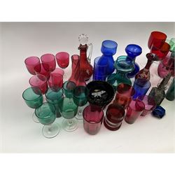 Group of Victorian and later coloured glassware, to include cranberry and emerald examples, largely drinking glasses in the form of wine glasses and tumblers, plus a Victorian pressed amethyst slag glass bowl with twin handles. 