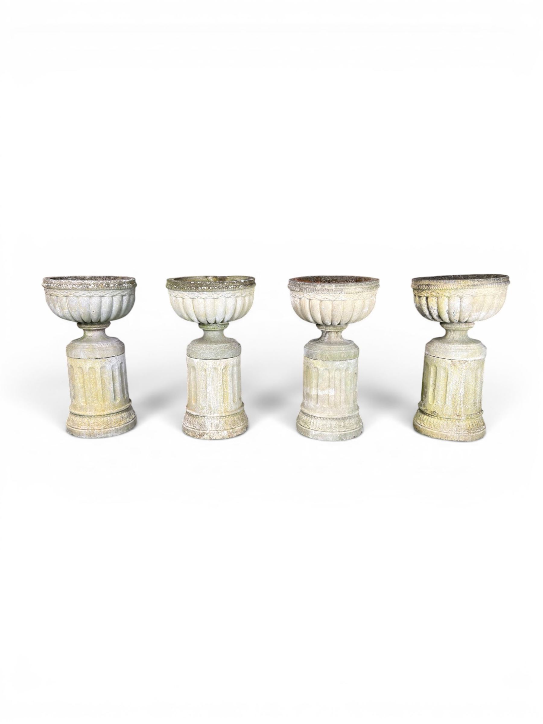 Four 20th century good quality weathered cast stone pedestal urns, circular lobed bowls with rope twist and lattice border, raised on squat base with fluted columns