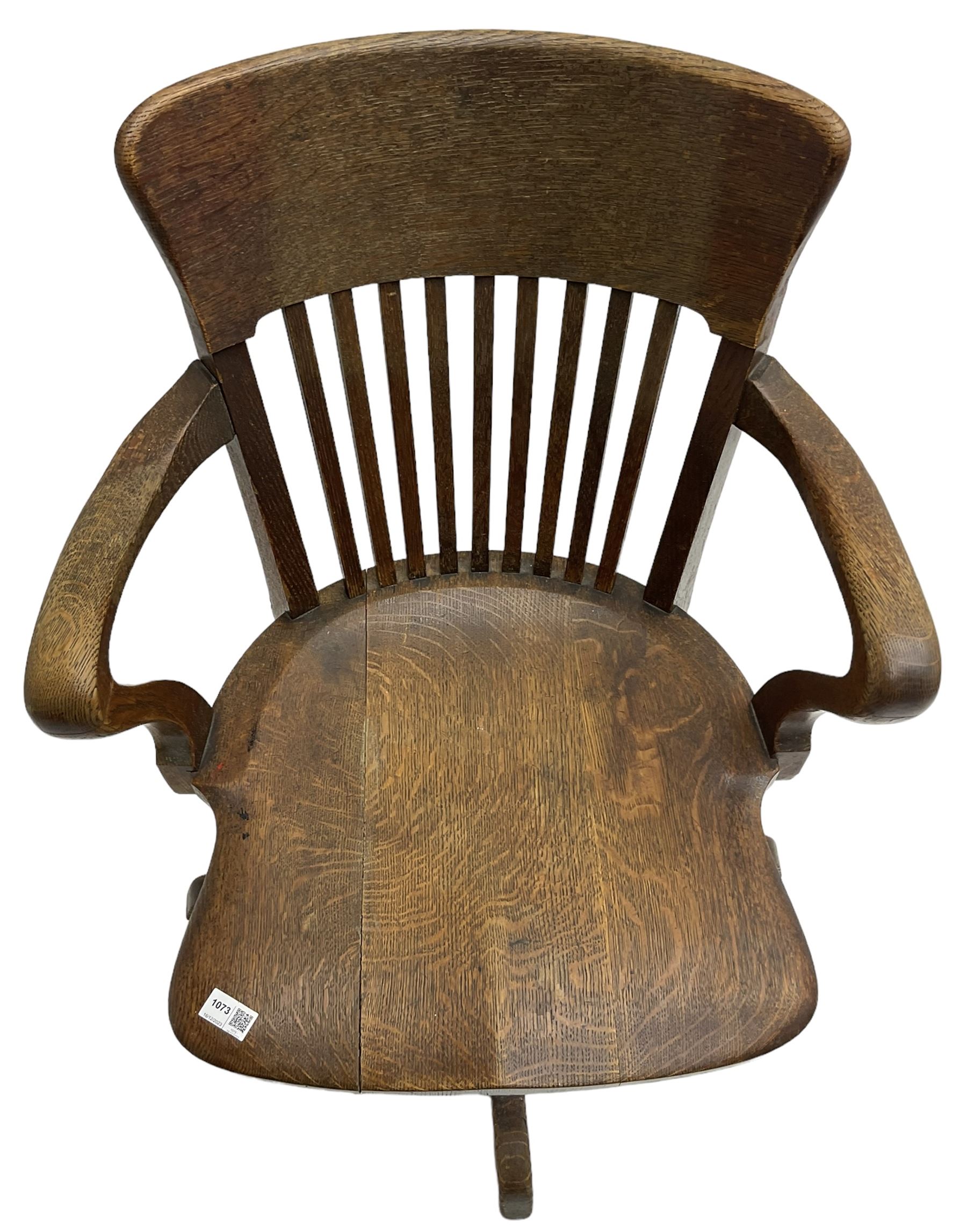 Early 20th century swivel office desk chair, shaped bar back over vertical rails, dished seat, on four splayed supports