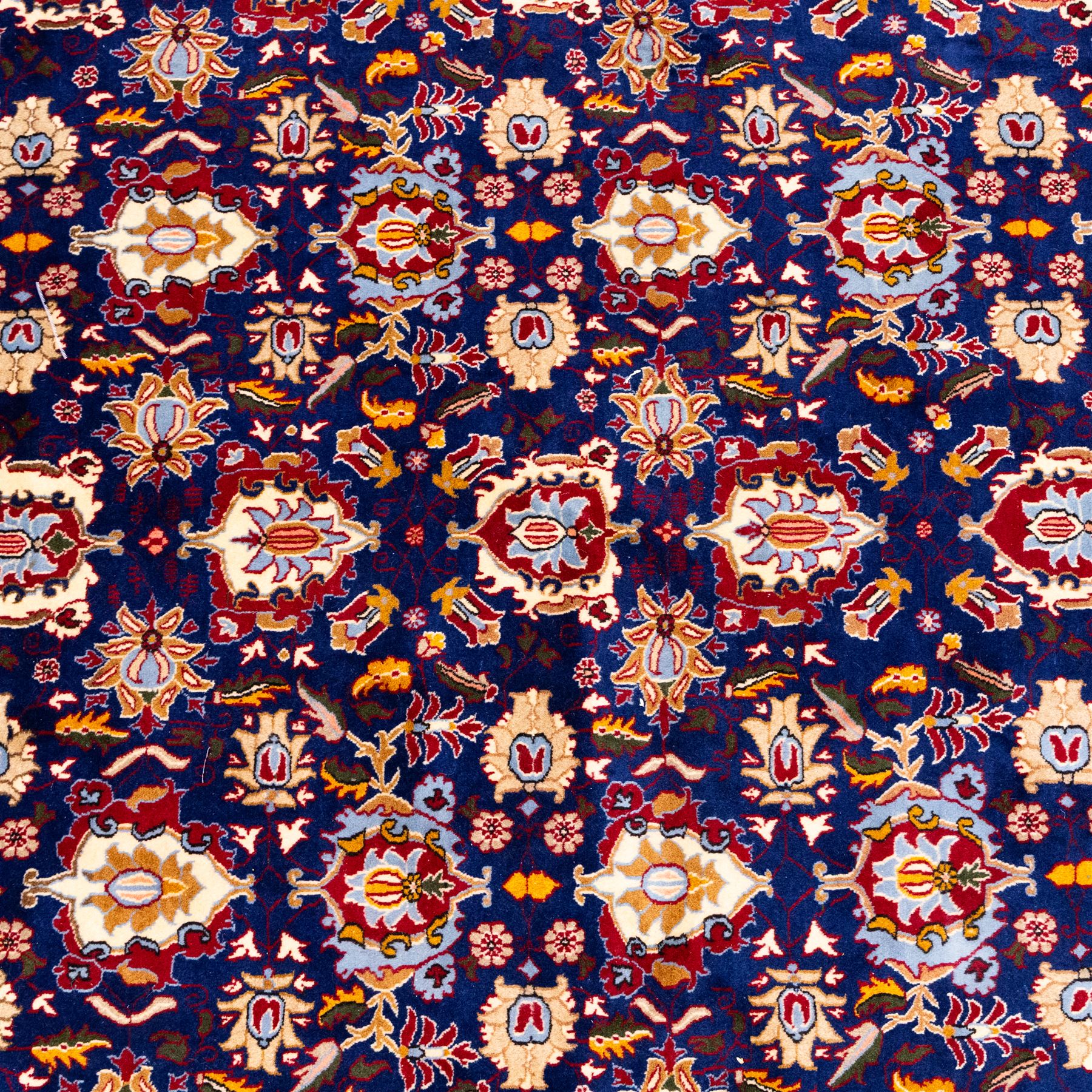 North Central Persian Veramin hand-knotted rug, deep indigo field decorated with an all-over lattice of stylized floral and palmette motifs issuing from an angular vine ornament, enclosed by a broad madder-red border of palmettes and scrolling vine devices between multiple guard stripes, with cotton fringe ends 