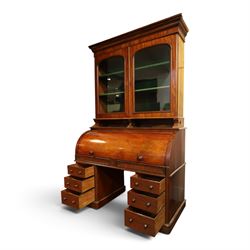 Victorian mahogany cylinder roll-top bookcase-secretaire, projecting cornice over twin glazed doors enclosing two shelves, the cylinder roll-top enclosing fitted interior with sliding drawer, hinged compartments, correspondence drawers and pigeon-holes, the twin pedestals fitted with three graduating drawers to each side, on plinth bases with castors