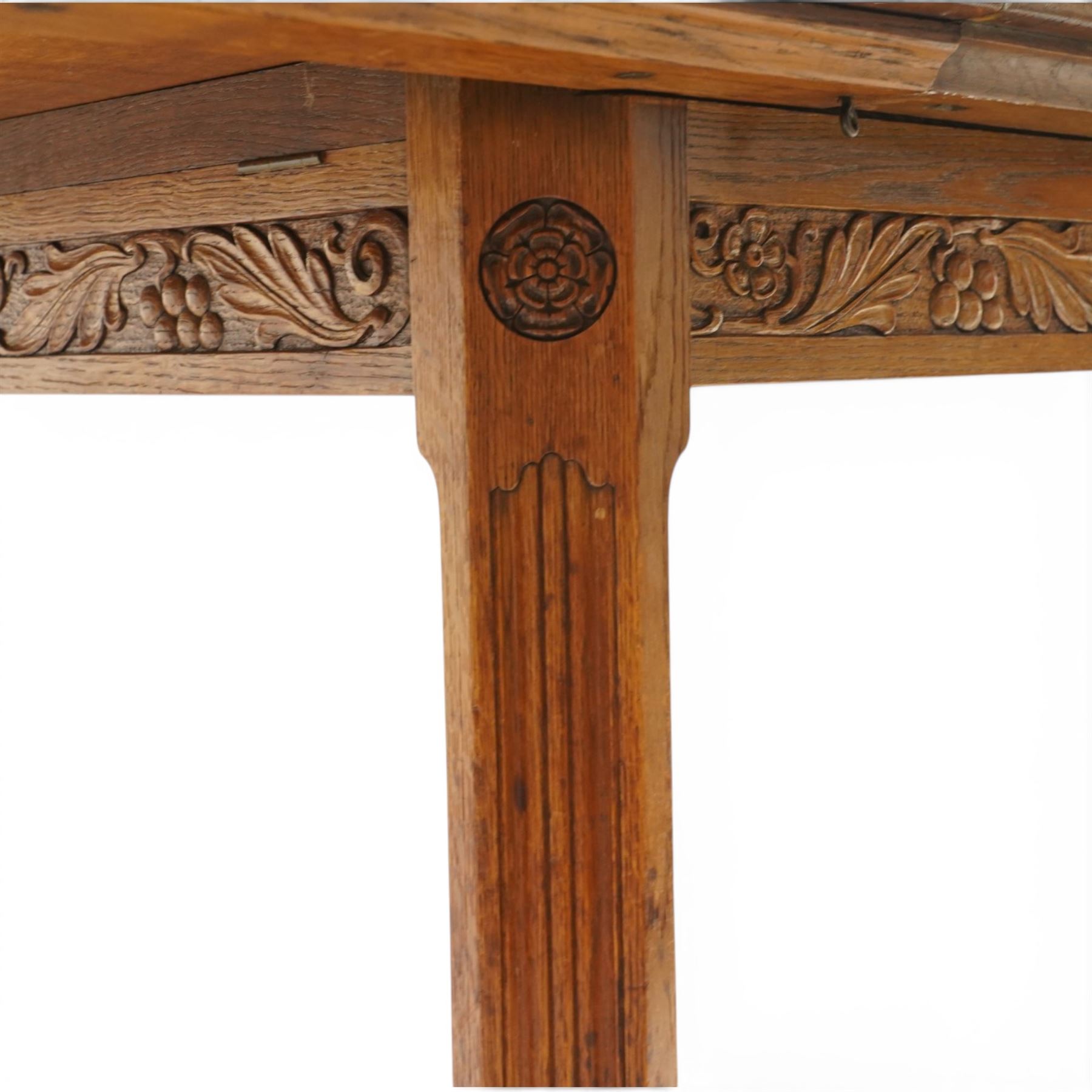 Waring & Gillow - Arts and Crafts oak draw-leaf extending dining table rectangular moulded top with chamfered corners, two additional leaves, carved frieze over fluted section supports, united by low X-shape stretchers