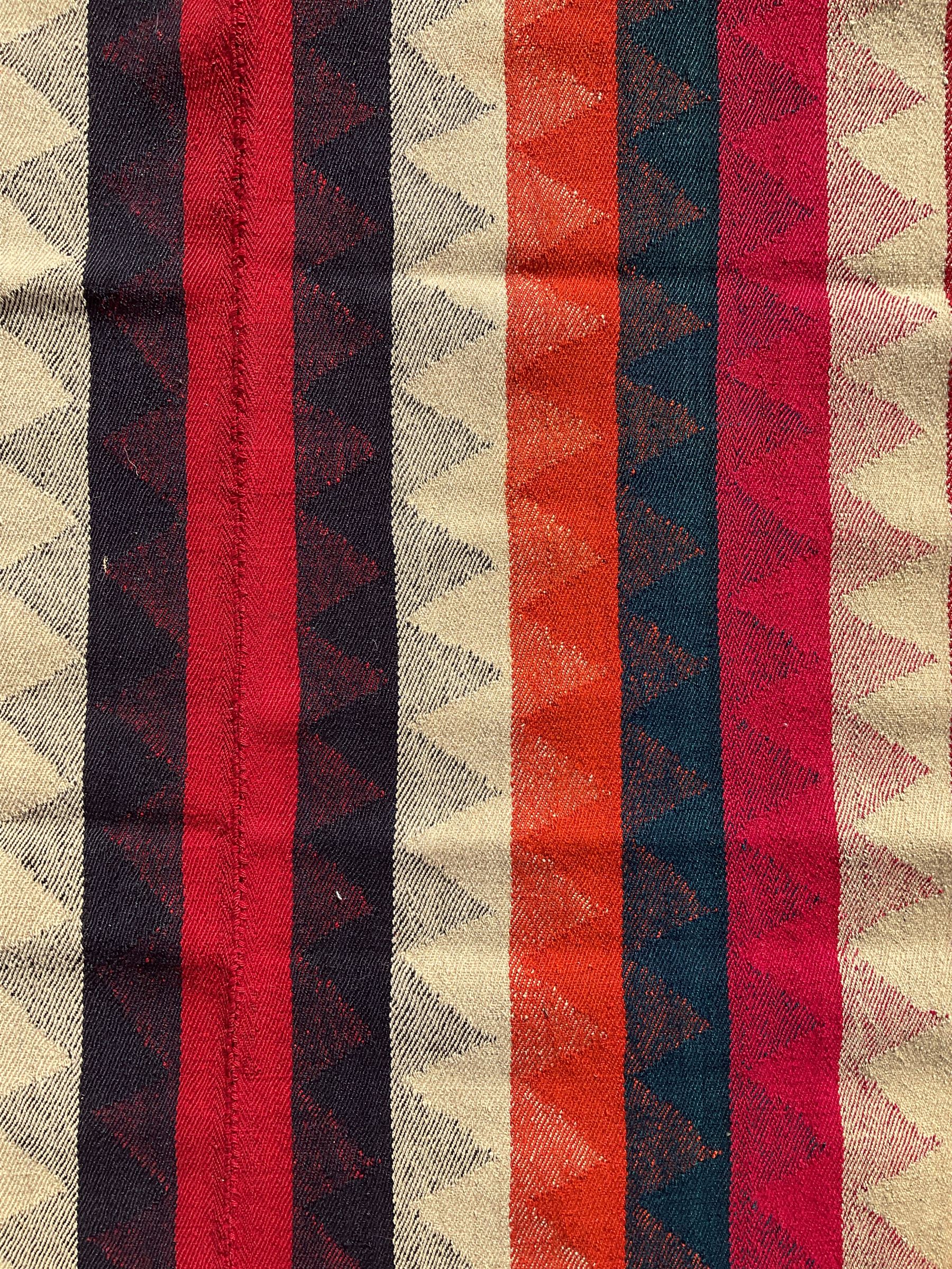 Southwest Persian Jajim Kilim ground rug, decorated with alternating vertical stripes in shades of crimson, orange, green, and black, with subtle triangular motifs woven into each stripe, bordered by narrow bands