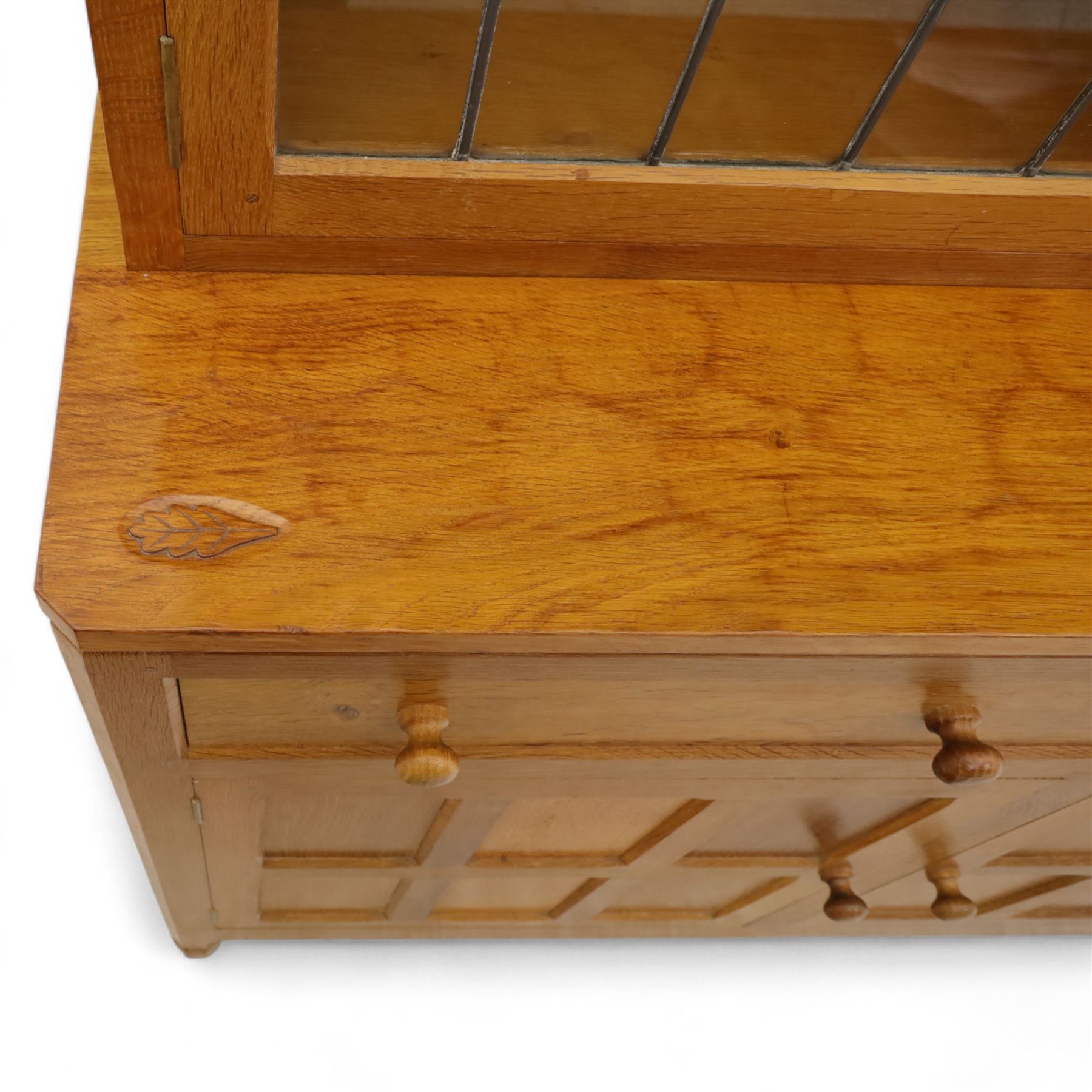 David 'Oakleafman' Langstaff - oak three drawer dresser, the scalloped cornice above a back with central open shelves flanked by two glazed and leaded cupboard doors opening to glass shelves, upon a base with adzed top carved with signature leaf, three drawers and three panelled cupboard doors with turned handles, upon octagonal feet, from the workshop of David Langstaff, Easingwold, Yorkshire