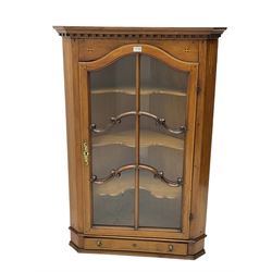 Early 20th century satinwood and mahogany inlaid corner cabinet, projecting dentil cornice over astragal glazed arched door with C-scroll glazing rails and ebony stringing, enclosing tree shelves with shaped fronts, single drawer to base with lion mask ring handles