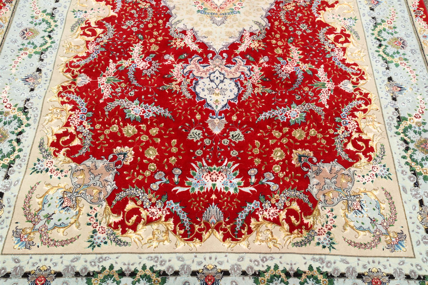 Fine Persian silk inlaid crimson ground Tabriz rug, the shaped field decorated with a central foliate pole medallion filled and surrounded by finely knotted floral motifs and trailing foliage, the cyan guard stripe with bold festoons and palmette motifs