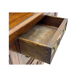 Late 19th century oak dresser, the upper section with two shelves beneath a shaped cornice, the lower section with a central bank of three drawers flanked by cupboard doors, all decorated with geometric diamond motifs, the drawers fitted with brass handles, raised on a shaped plinth base