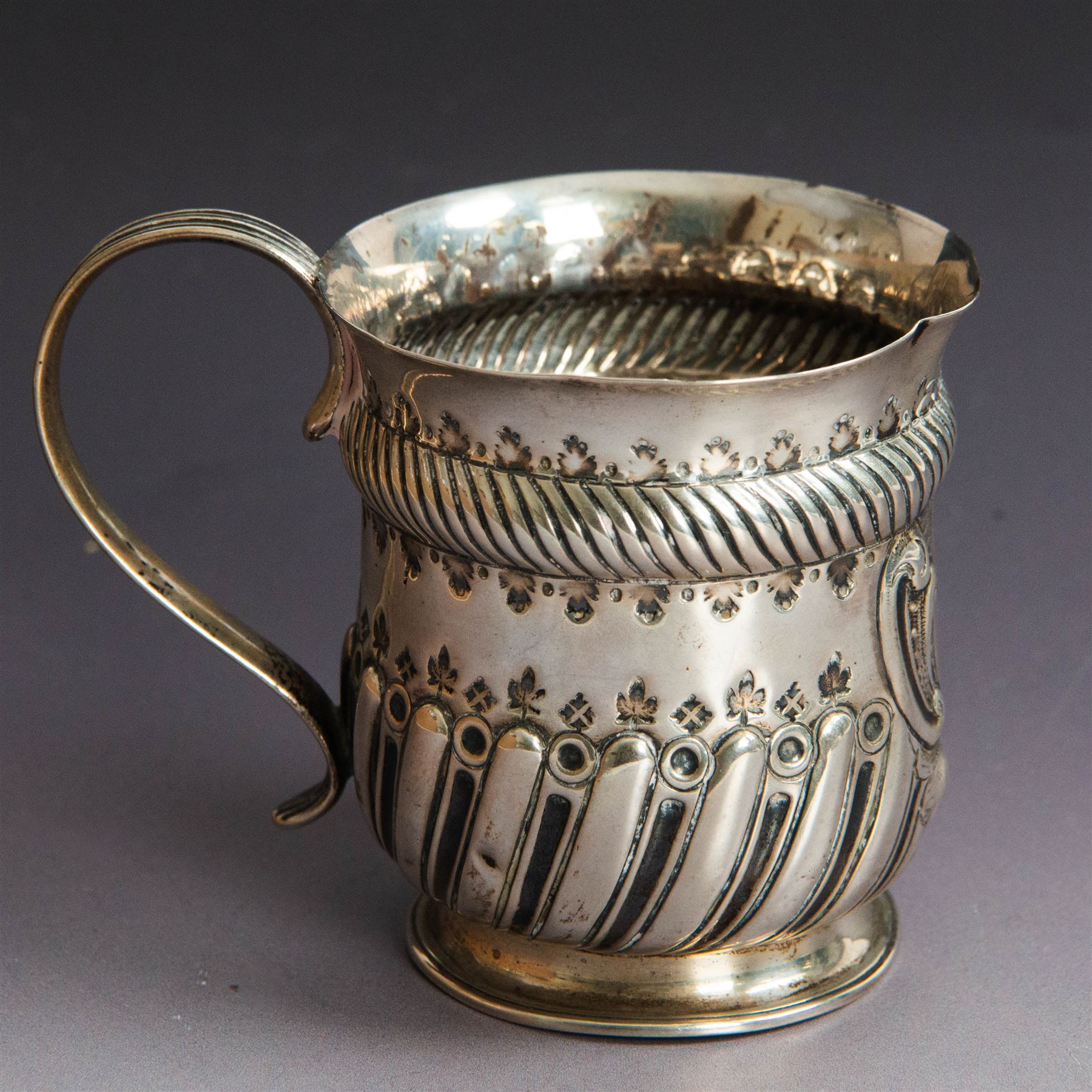 Victorian silver christening mug, of circular form with C scroll handle, embossed with scrolls and foliate decoration, with vacant oval cartouche to body, hallmarked John Aldwinckle & Thomas Slater, London 1890, contained within a tooled leather fitted case, mug H8cm