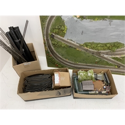 '00' gauge model railway layout of oblong form on six removable tubular legs, the outer loop enclosing further track amongst simulated grass and mossy vegetation, box of removed buildings and accessories and large quantity of additional track included 183 x 108cm
