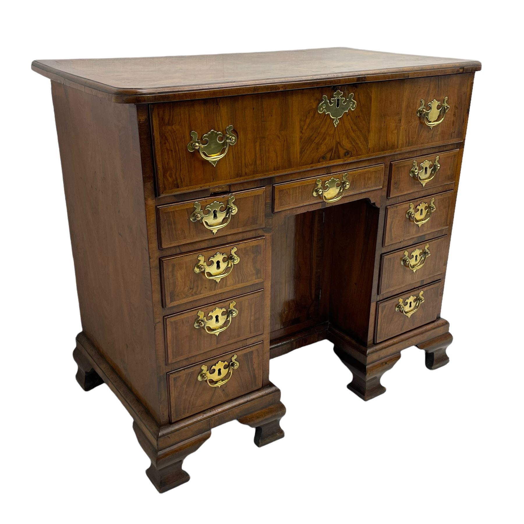 Early 18th century Queen Anne figured walnut kneehole desk with secretaire drawer, moulded and book matched top with walnut band, the top drawer with fall front enclosing small drawers and pigeon holes, fitted with nine drawers and central recessed cupboard, on ogee bracket feet