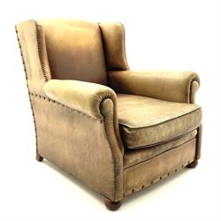 Wing back armchair upholstered in studded tan leather