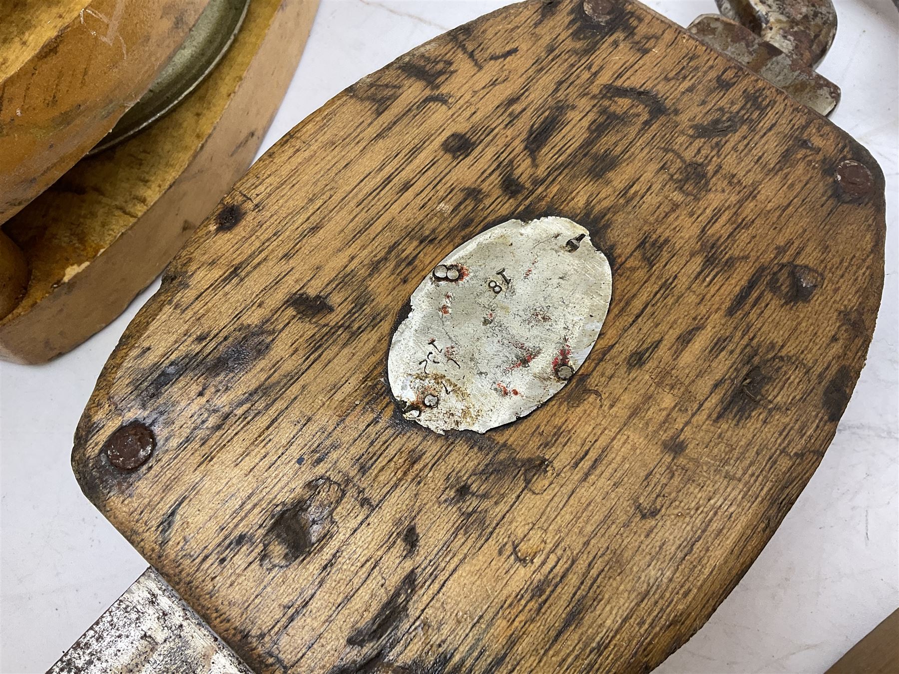 Three ship pulleys comprising wooden block double with swivel eye marked 'wooden block 240mm double rope: 22mm',  wooden block double with upset shackle and wooden block with stiff swivel hook, largest example L50cm