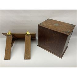 Early 20th century oak smokers cabinet, with brass shield shaped mounts, opening to reveal a compartmentalised interior with three drawers, pipe rack and tobacco jar, together with a small wooden shelf, smokers cabinet H28.5cm