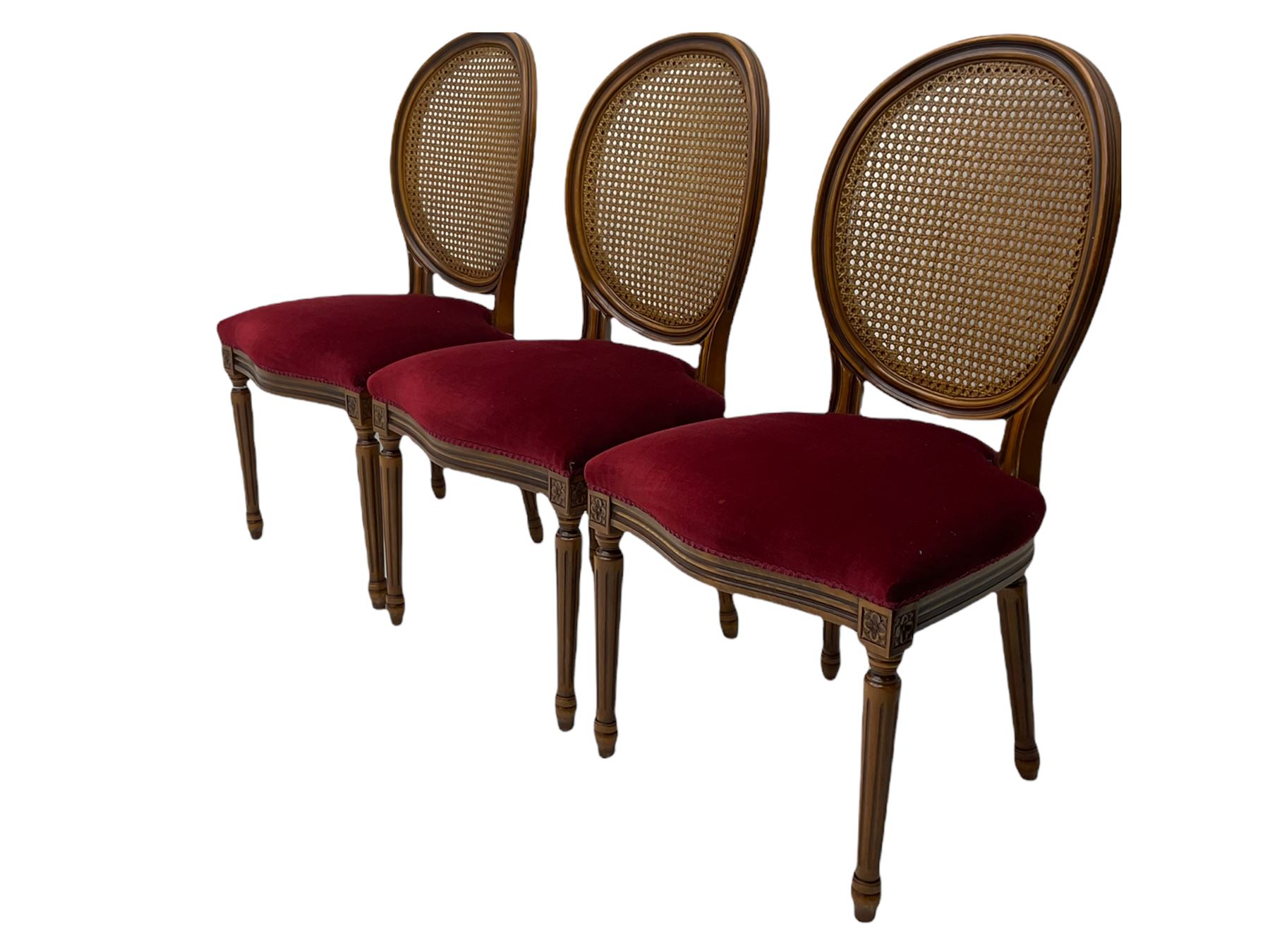 Set six French style walnut finish dining chairs, oval cane bergere backs over serpentine seats upholstered in red, flower head carved fluted supports