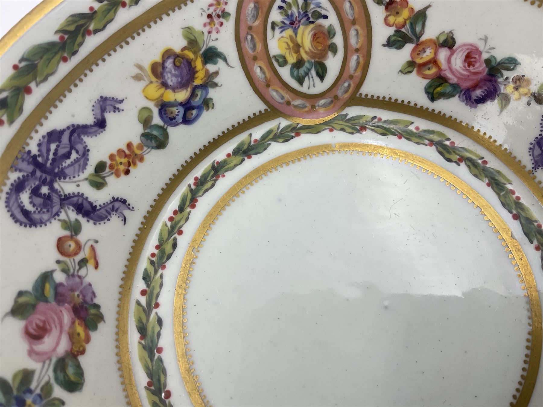 Sèvres soft paste porcelain coffee can and saucer with date code for 1780, painted with pink oval panels bordering bouquets of flowers, united by swags of flowers tied with purple ribbons, within laurel leaf borders, interlaced LL monogram enclosing date letters CC above painters marks for Nicquet, coffee can H7.5cm, saucer D15cm