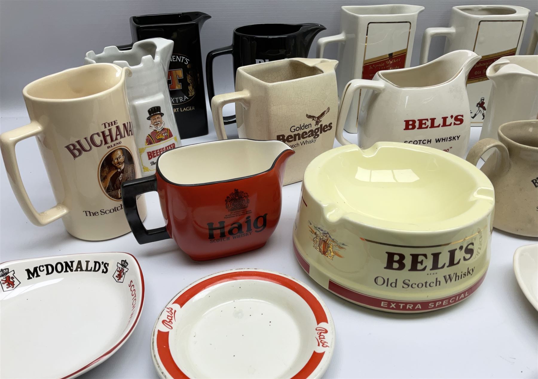 Collection of ceramic pub jugs and ashtrays, including Senior Service ashtray, Bell's old scotch whiskey ashtray,Arthur Bell & sons jug, Beefeater gin jug, two Black and White scotch whiskey jugs, etc    