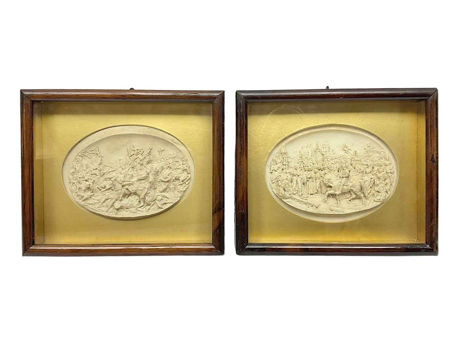 Justin Mathieu, two oval high relief plaque depicting a battle scenes, each within a wooden frame, frame  H21cm, L25cm