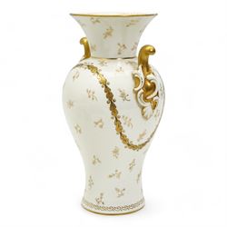 Early 20th century Royal Worcester porcelain twin handled vase, circa 1910, painted with a basket of flowers by Ernest Phillips, within an oval gilt border, the plain ground decorated with gilt sprigs and trailing oak leaves, signed, printed marks beneath, H21.5cm