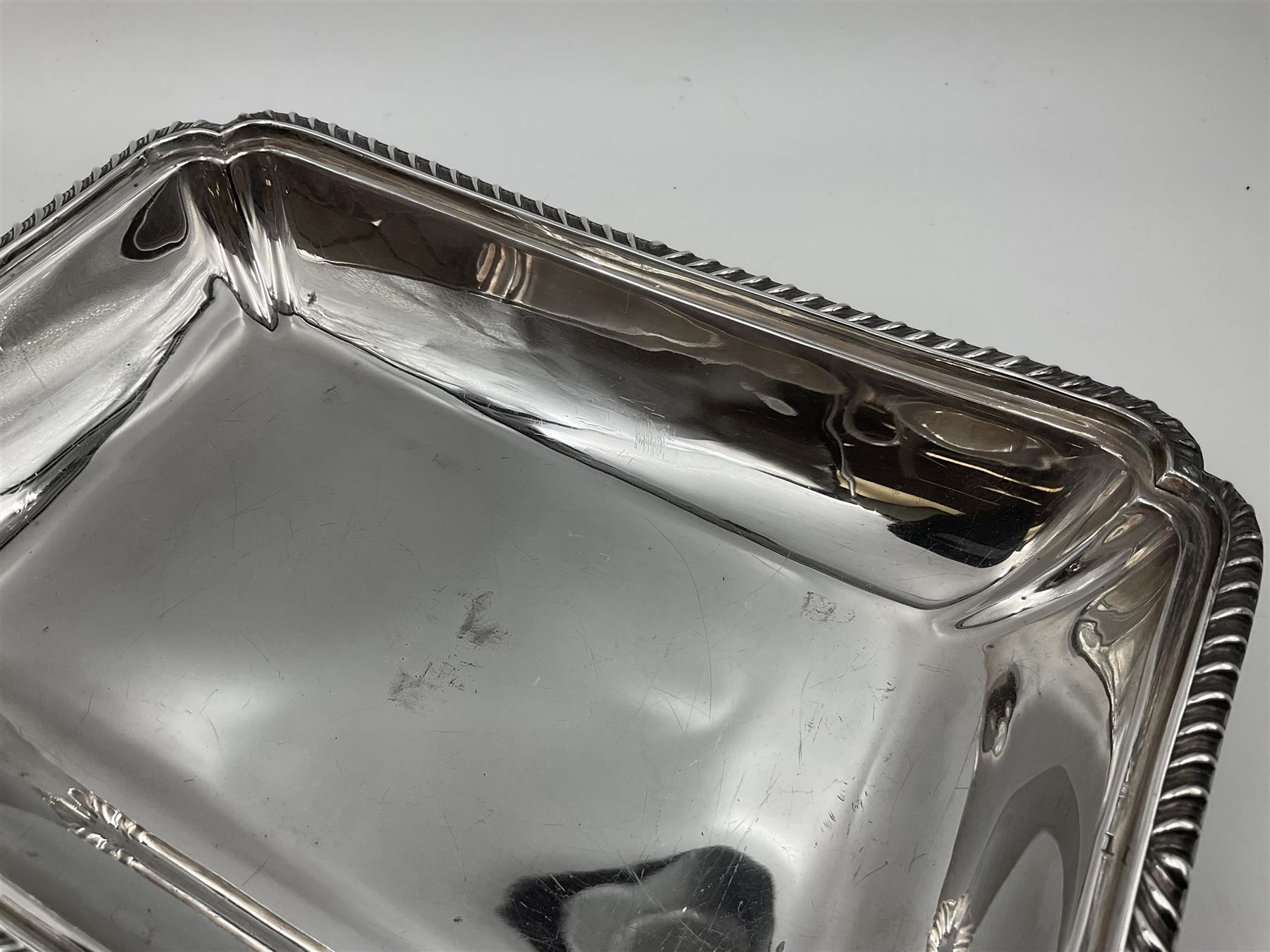 Early 20th century silver entree dish and cover, of rectangular form with shaped corners and oblique gadrooned borders to base and cover, the cover with loop 'bamboo' handle, hallmarked Thomas Bradbury & Sons Ltd, Sheffield 1930, including handle H10.5cm L24.5cm