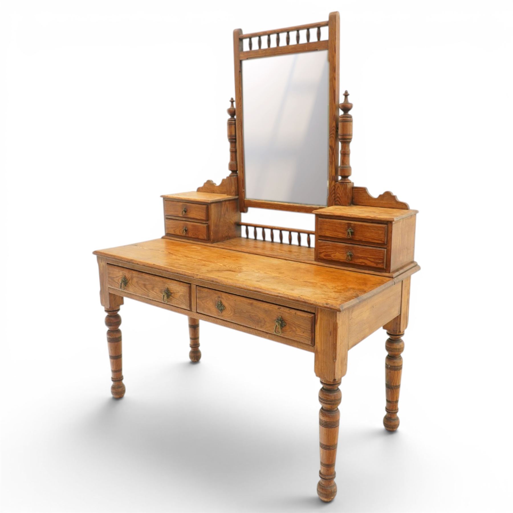 Victorian stripped pine dressing table, rectangular top over two drawers with brass handles, the raised back fitted with adjustable rectangular mirror, spindle gallery flanked by two short jewellery drawers either side, on turned legs
