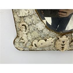 Pair 19th century French Dieppe bone and ivory wall mirrors, the oval bevelled mirror plates within rectangular frames with shaped tops, profusely decorated with ivory leaves, further detailed with carved bone armorial type crest inscribed 'SGOTORVM', putti, fish and mask heads, H81cm W48cm
