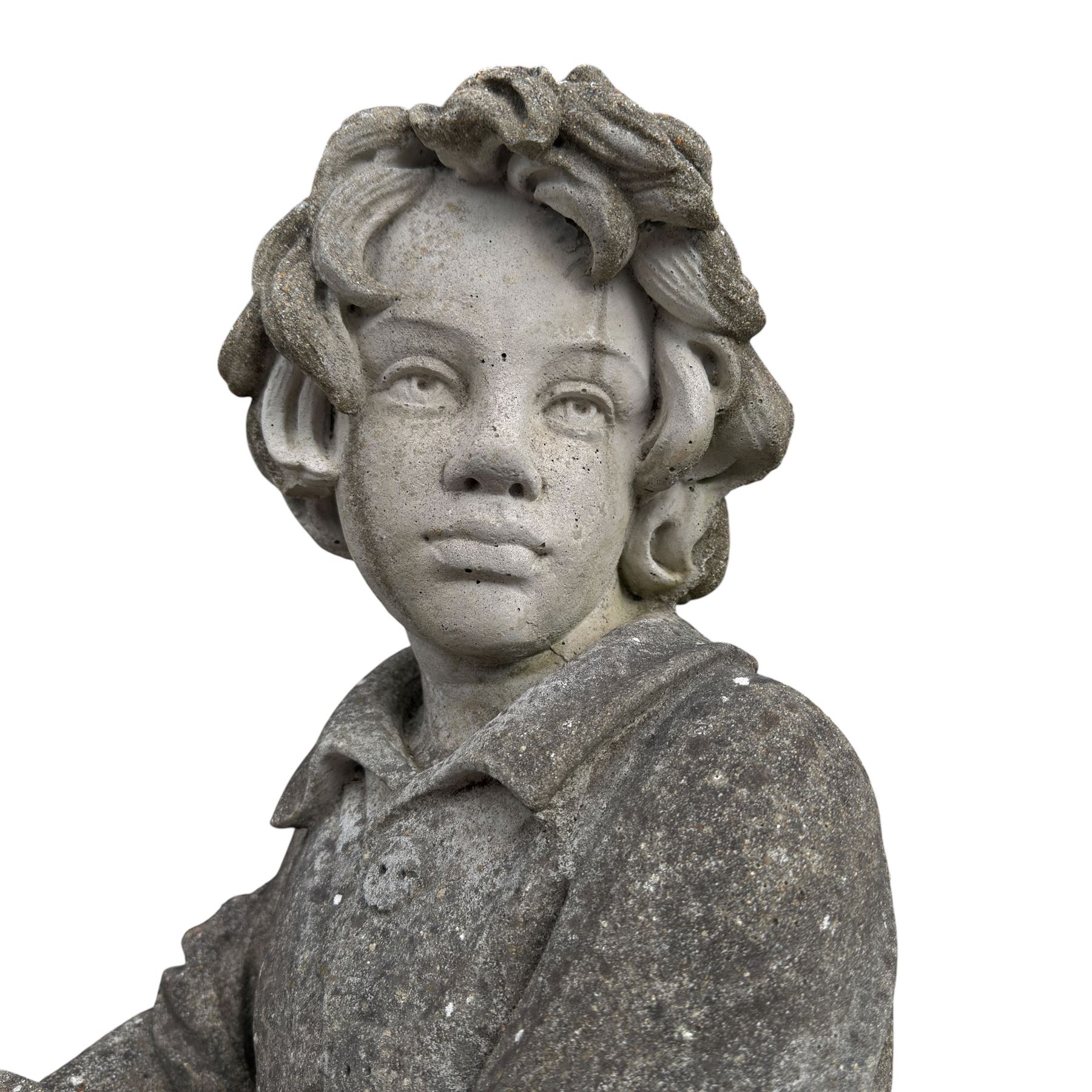 Haddonstone - weathered cast stone garden statue of a boy holding a basket of grapes, modelled with curled locks of hair wearing a tunic and breeches leaning against a naturalistic tree stump, on square base