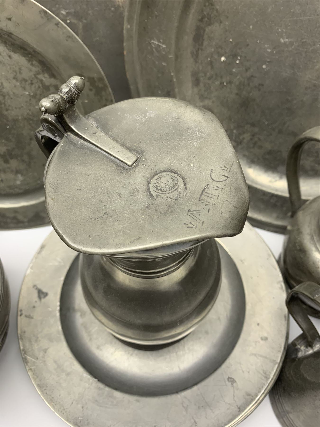 Collection of 18th and 19th century pewter, comprising two chargers, eight large plates, twenty six smaller plates, two bowls, three lidded measures, two jugs, tappit hen, and tankard, the plates with various marks and touch marks, including pseudo 'hallmarks', largest charger 37cm, large plates D30cm, smaller plates D24.5cm, tappit hen H26.5cm