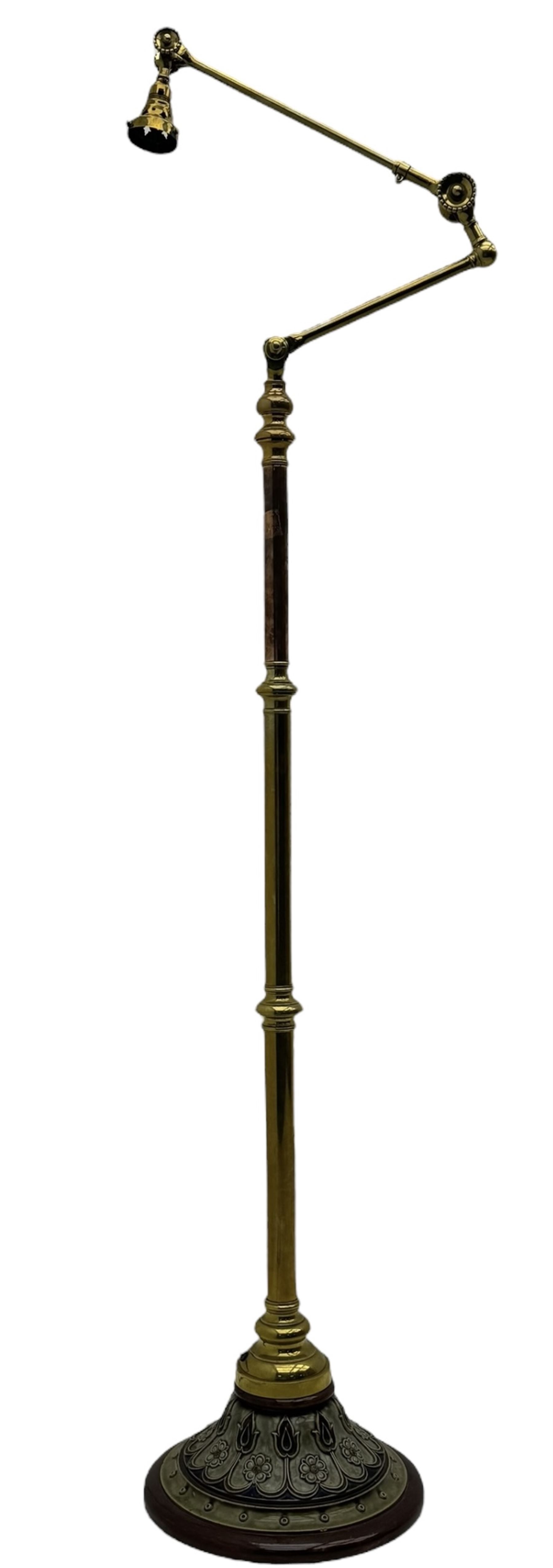 Early 20th century brass adjustable floor lamp, Royal Doulton decorative ceramic base embellished with raised floral and scroll patterns, stamped, brass column and adjustable arms terminating in brass bulb holder
