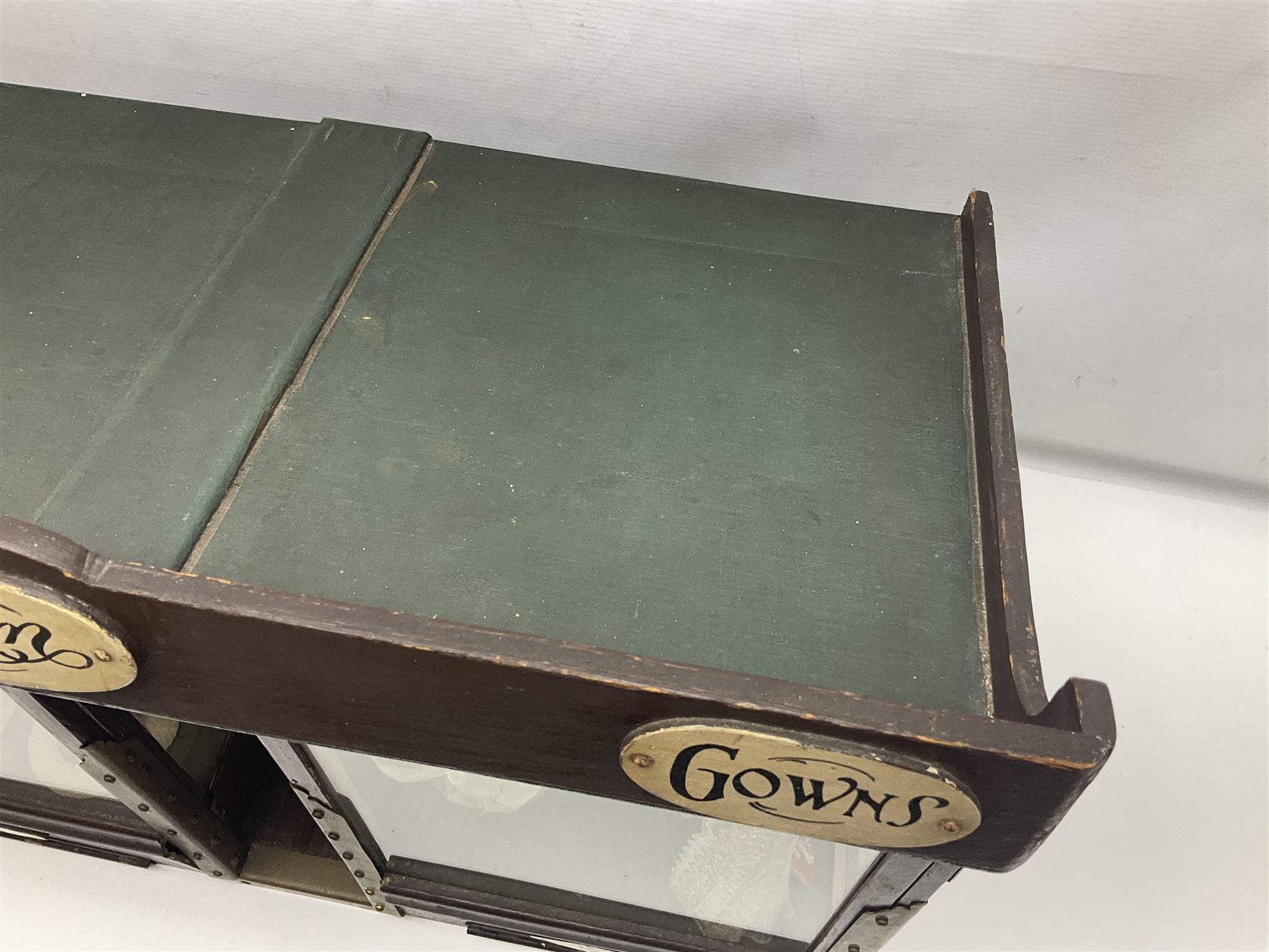 Early 20th century scratch-built wooden hat & gown shop diorama 'Joan', of double-fronted form glazed on three sides with brass and aluminium mounts, rear access apertures and storage under L63cm H45cm D31cm; with small collection of dresses and hats on display stands