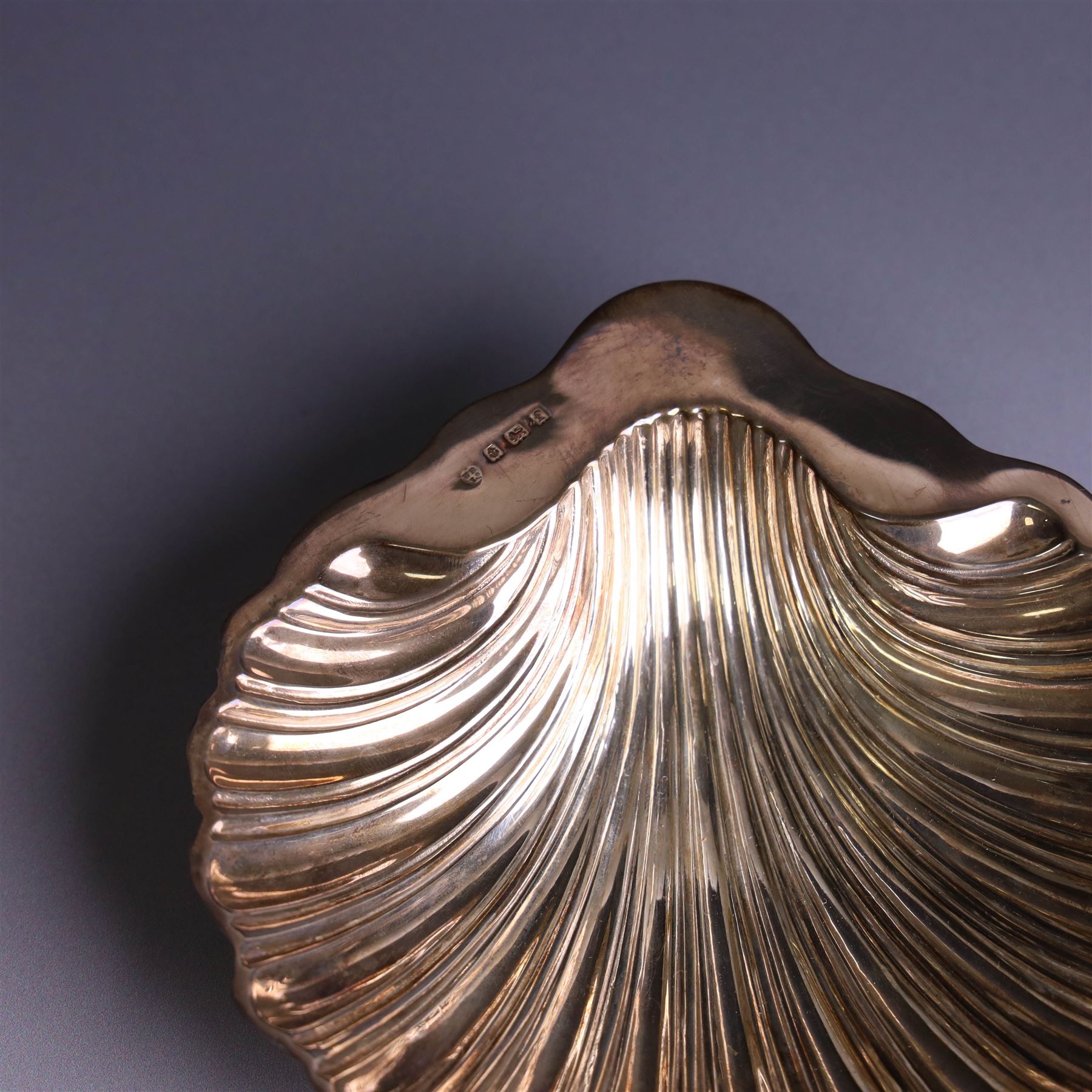 Edwardian silver butterdish in the form of a clam shell and upon four bun feet, hallmarked Williams Birmingham Ltd, Birmingham 1905, with a silver plated butter knife, contained within a fitted tooled leather case, width of dish 13cm