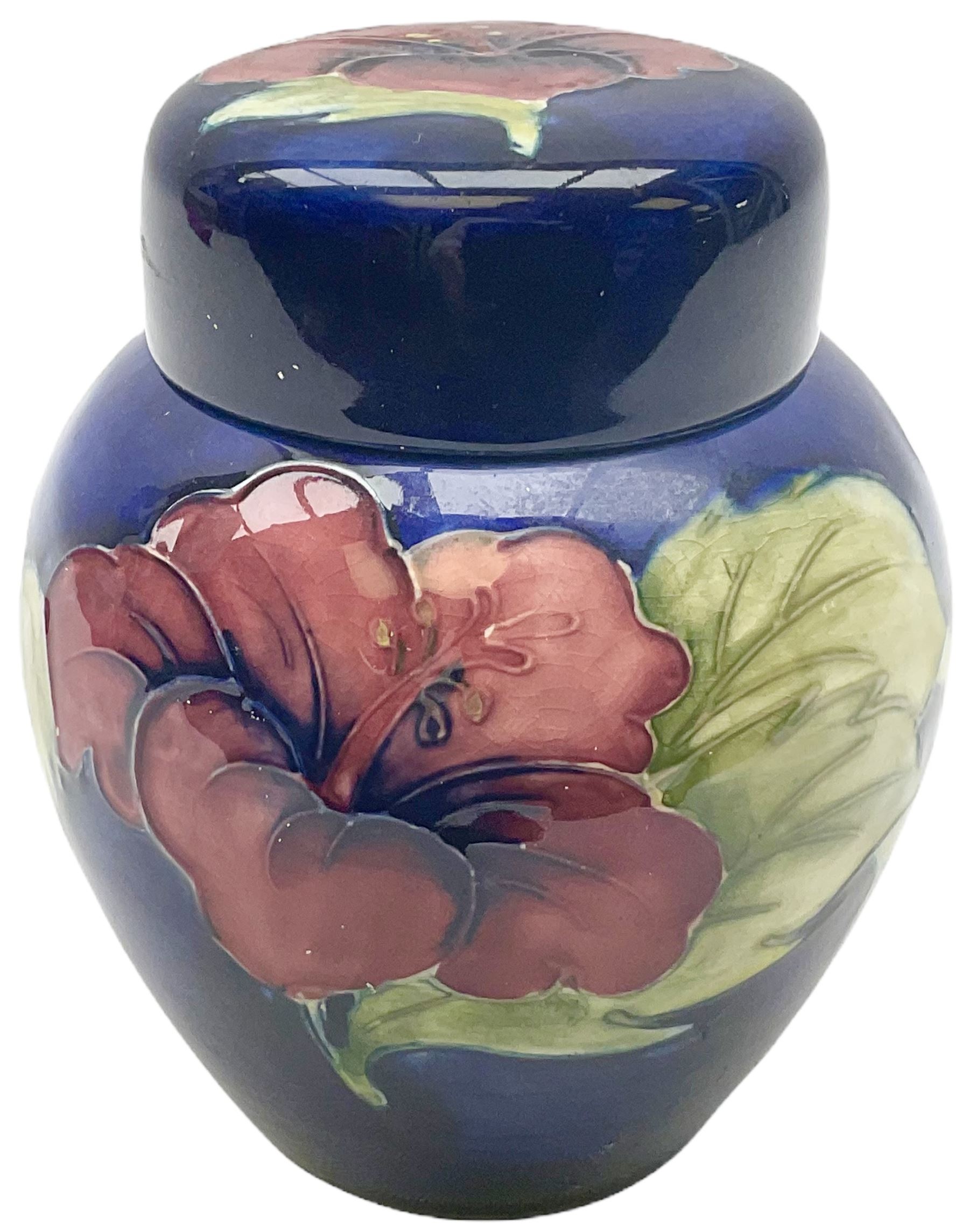 Moorcroft ginger jar, decorated in the Hibiscus pattern upon a blue ground, with paper label beneath detailed 'Potters to the late Queen Mary', H11cm.