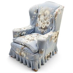 Pair of Queen Anne wingback armchairs, high back over out-swept arms, raised on ball-and-claw feet, upholstered in sky-blue ground floral chintz loose upholstery with pleated skirt and squab cushion